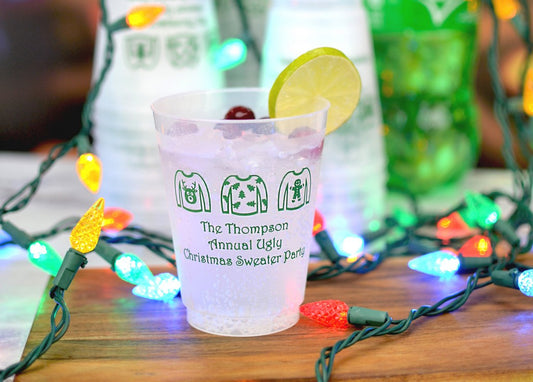 Festive plastic cup with holiday sweater design and lemon slice surrounded by colorful Christmas lights for the ultimate guide to Christmas party planning part 3
