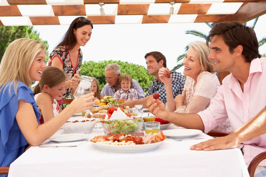 Family enjoying a meal together outdoors under a pergola showcasing how to plan the perfect family reunion