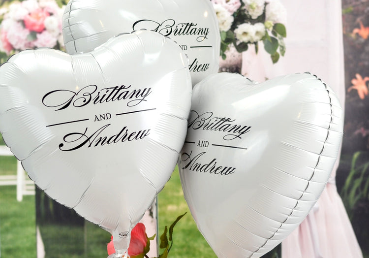 Personalized wedding balloons with custom names in elegant script on silver heart-shaped Mylar balloons