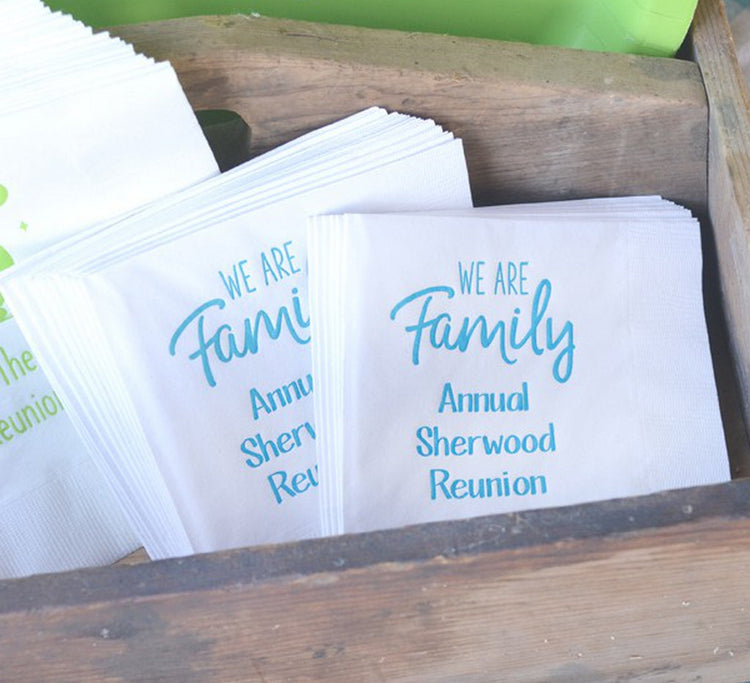 Stack of personalized family reunion napkins with blue text for Annual Sherwood Reunion in wooden box