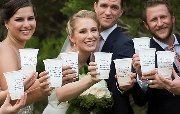 Bride and groom with wedding party holding personalized wedding reception cups