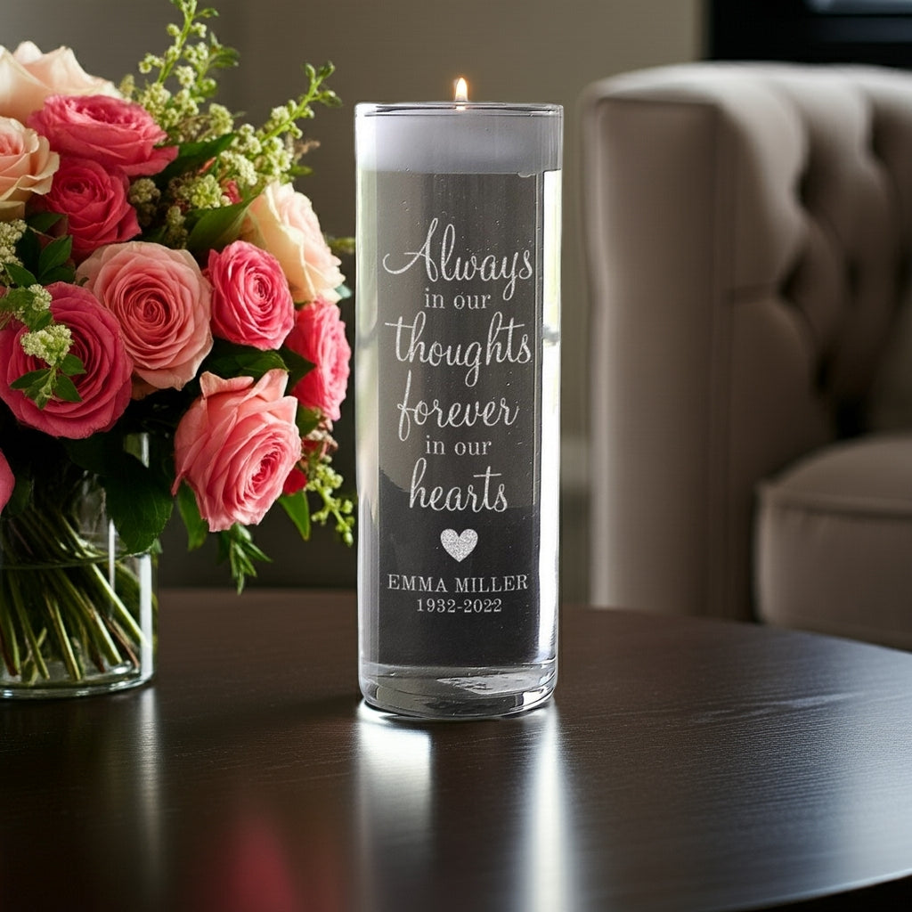 Personalized memory candle vase with engraved memorial text beside a bouquet of pink roses on a table