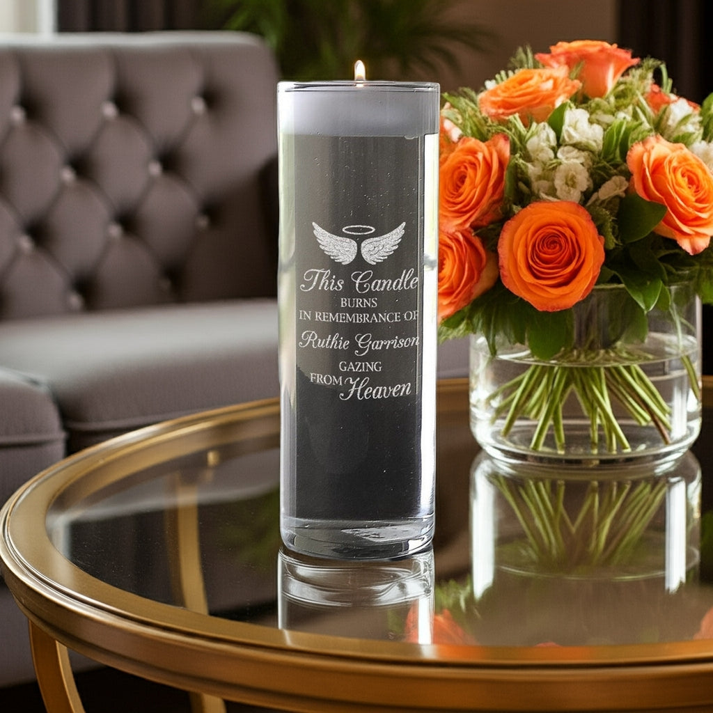 Angel Wings Personalized Memory Candle Vase with a burning candle on glass table beside orange flower arrangement