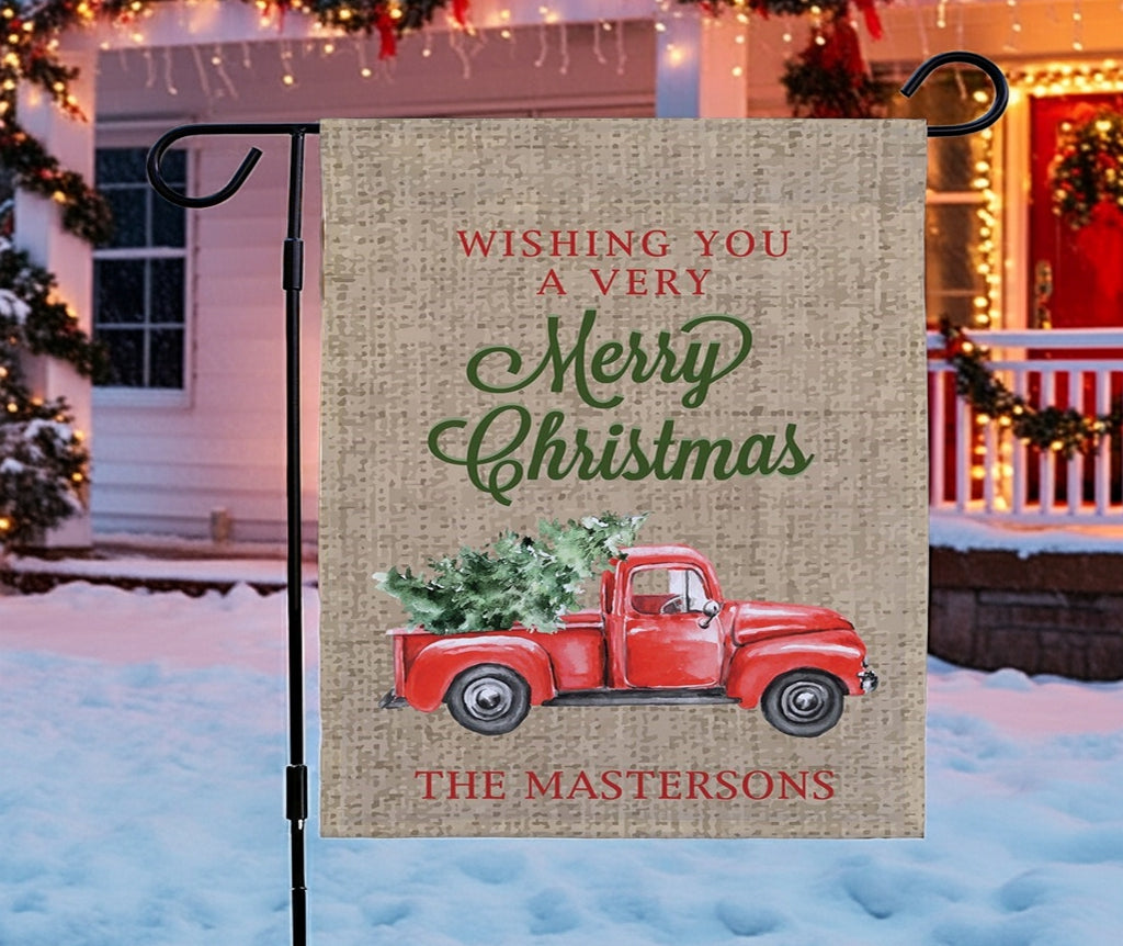 Christmas garden flag featuring a red truck with a Christmas tree and festive greetings