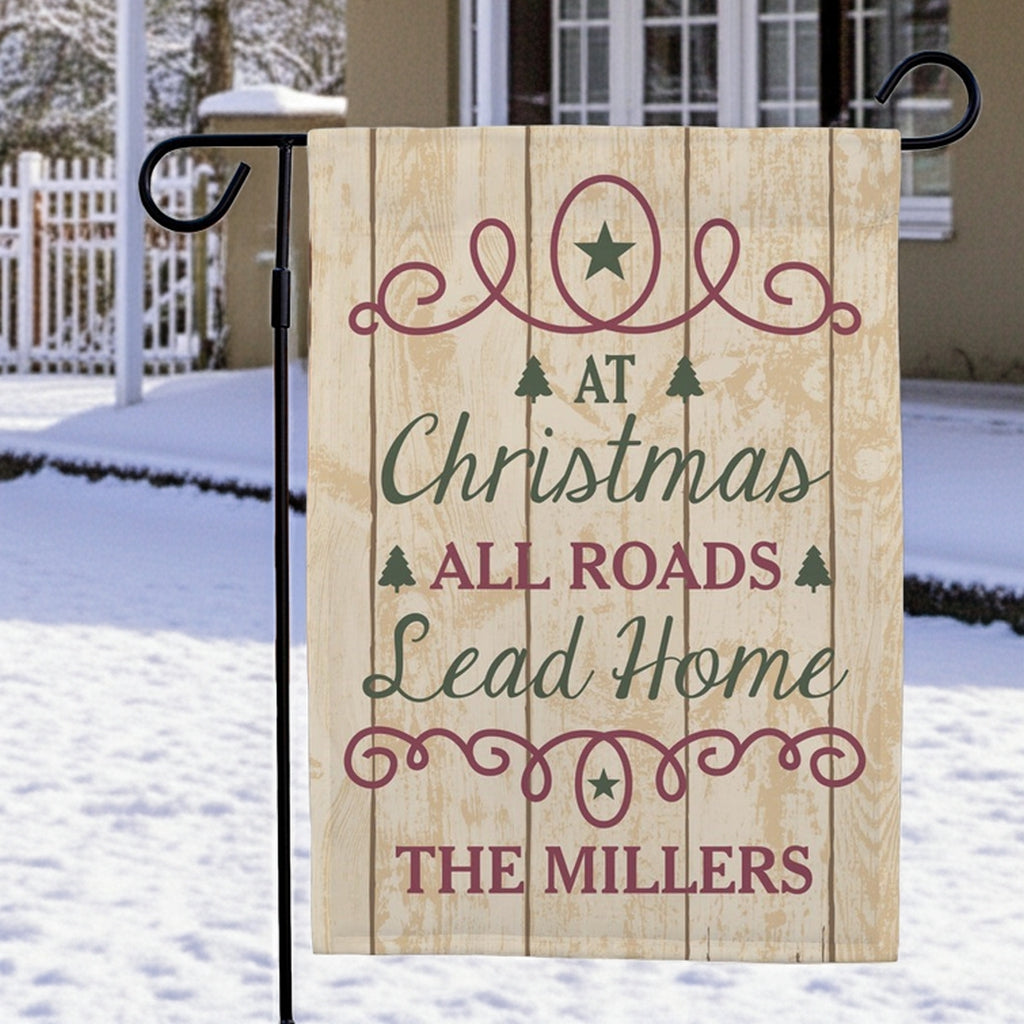 Christmas garden flag with a rustic design featuring 'At Christmas All Roads Lead Home The Millers'