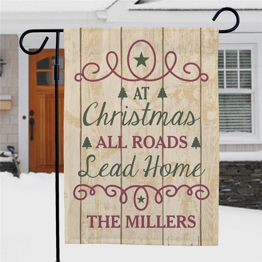 Personalized Christmas garden flag with a rustic design featuring the message At Christmas All Roads Lead Home