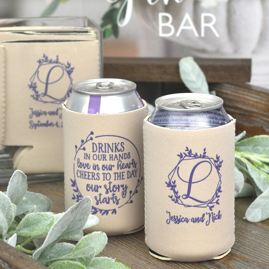 Sandstone color wedding can coolers personalized with geometric wreath initial design and bride and groom name on front side and drinks in our hands design on back side in lavender print