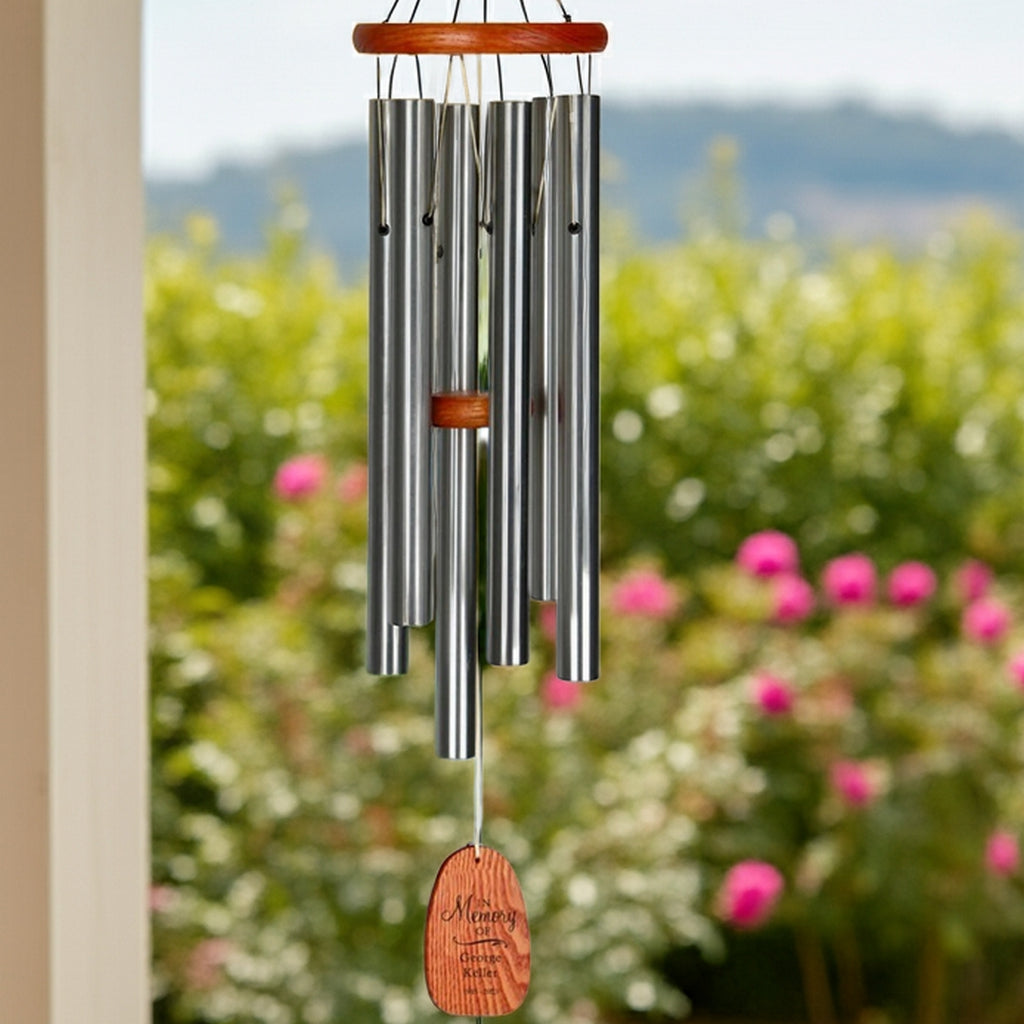 Engraved in loving memory wind chime with metal tubes and wooden accents hanging outdoors