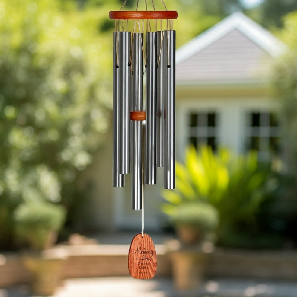 Engraved in loving memory wind chime with wooden top and metal tubes hanging outdoors