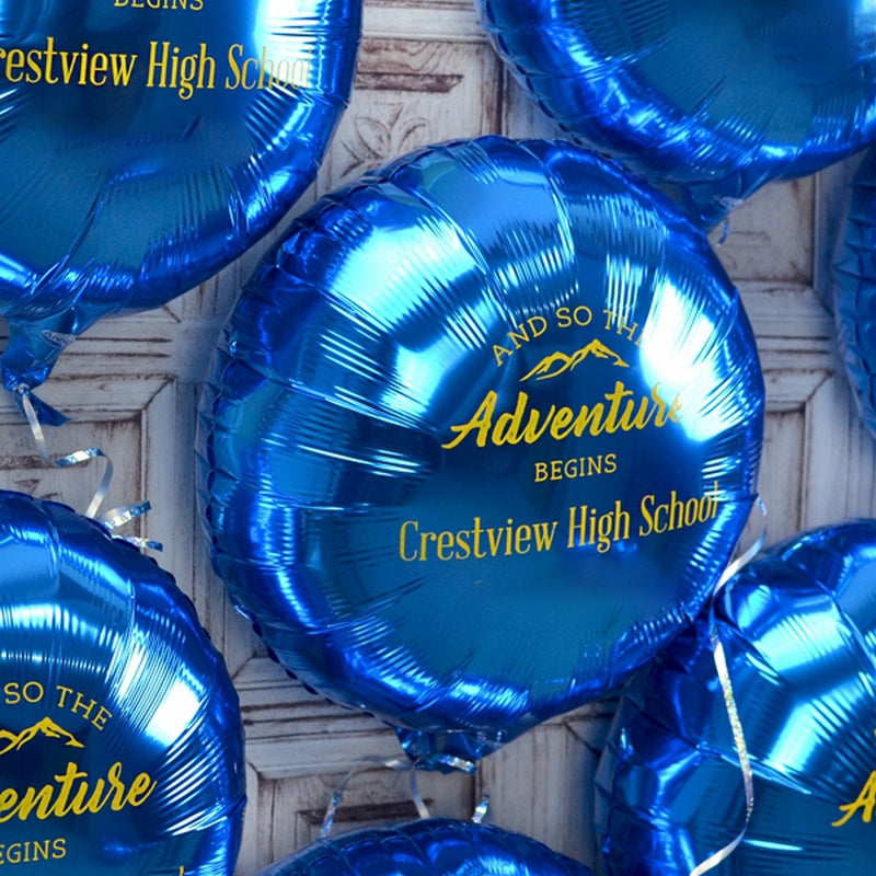 This stunning image showcases a vibrant collection of graduation party decorations featuring glossy blue balloons, each elegantly inscribed with the uplifting message "And So The Adventure Begins" in bold gold lettering. The balloons also highlight "Crestview High School" in a stylish font, adding a personalized touch for the graduating class. The design includes a subtle mountain graphic, symbolizing the journey ahead, making these balloons a perfect fit for high school graduation celebrations.