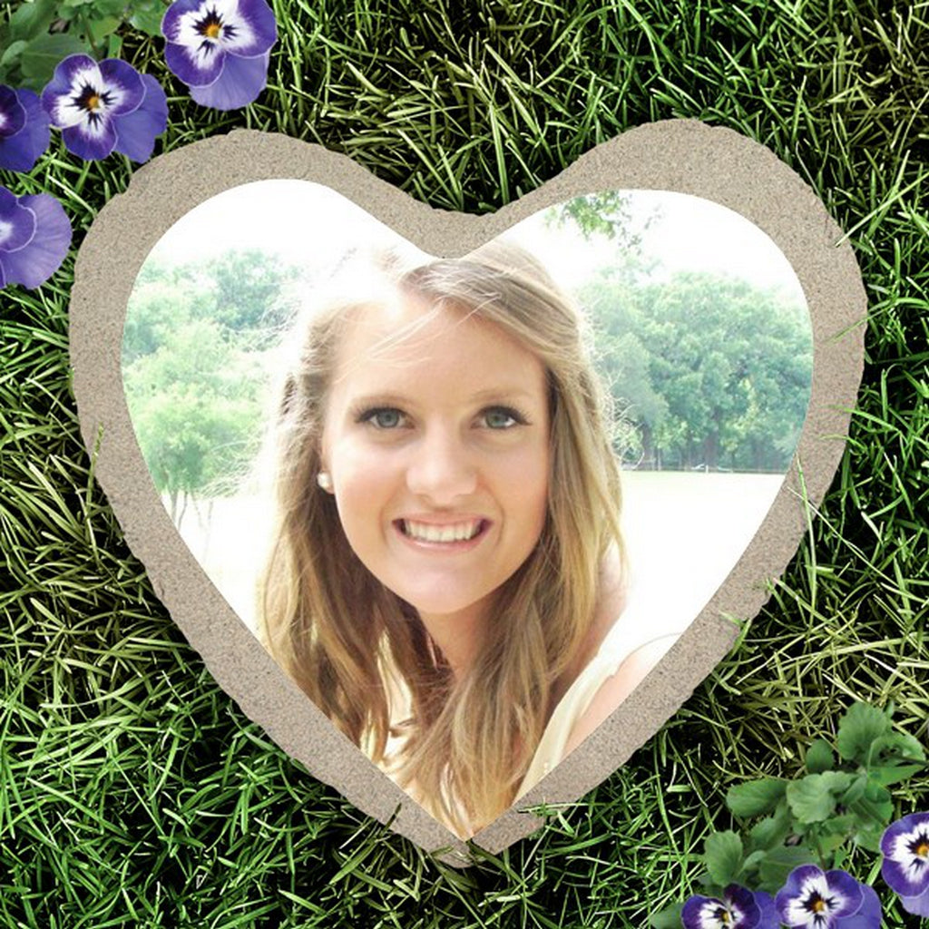 Heart shape custom photo garden stone with a personalized image on grass surrounded by purple flowers