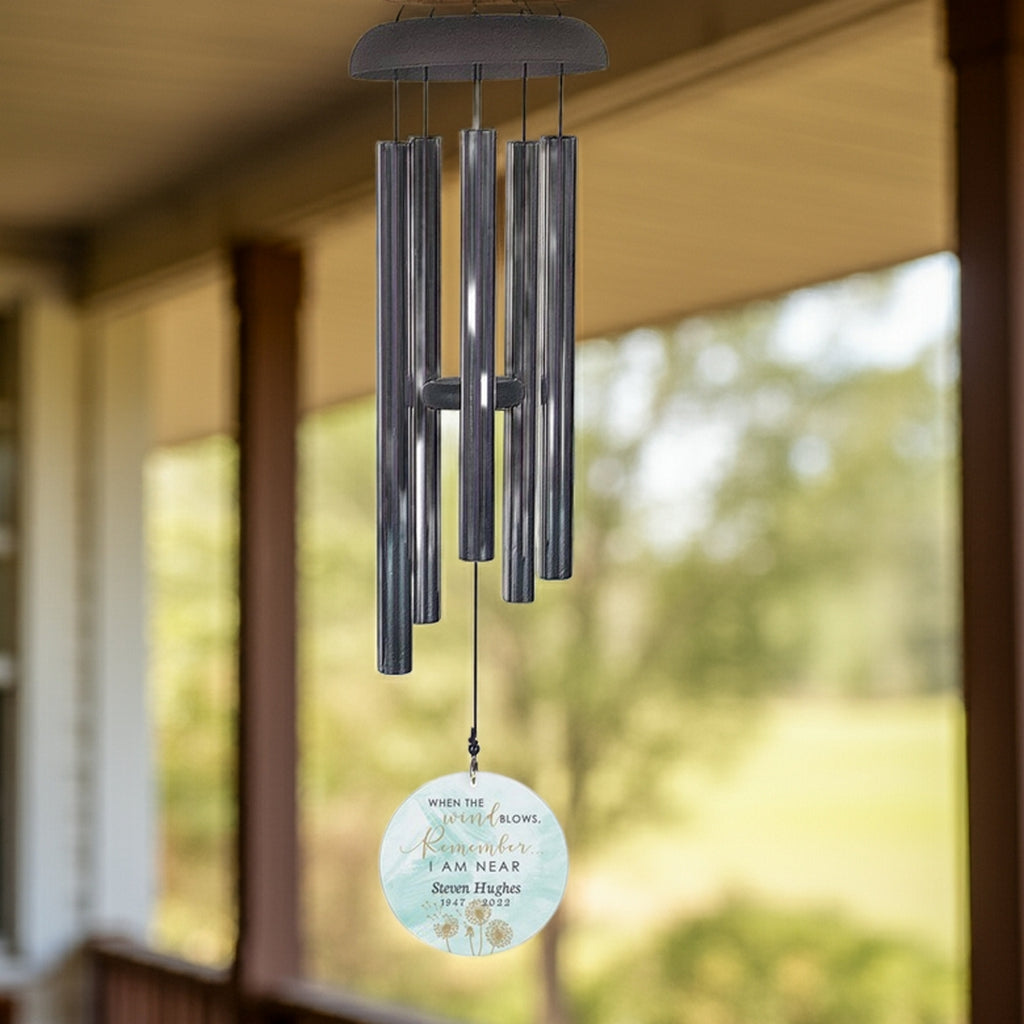 Personalized memorial wind chime with metal tubes and custom engraved round pendant hanging outdoors