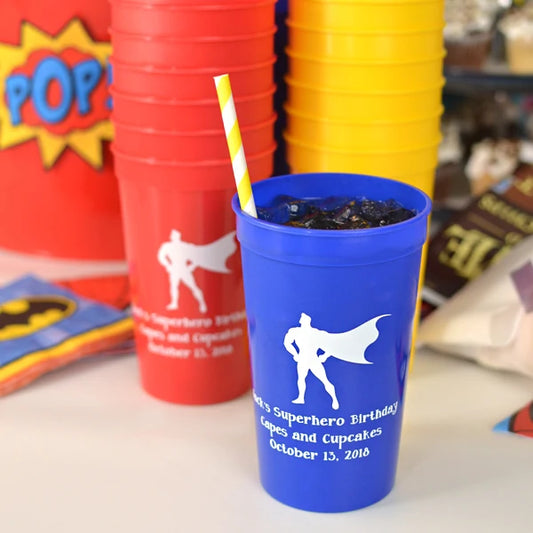 Blue, red and yellow 22 ounce plastic stadium favor cups for kids party personalized with 'sperhero design and 3 lines of custom text in white print