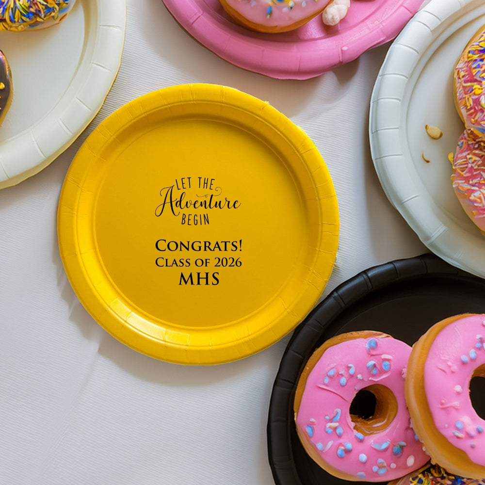 A Yellow paper grad party plate personalized with "Let the Adventure Begin" design and text "Congrats! Class of 2026, MHS" in black print with donuts