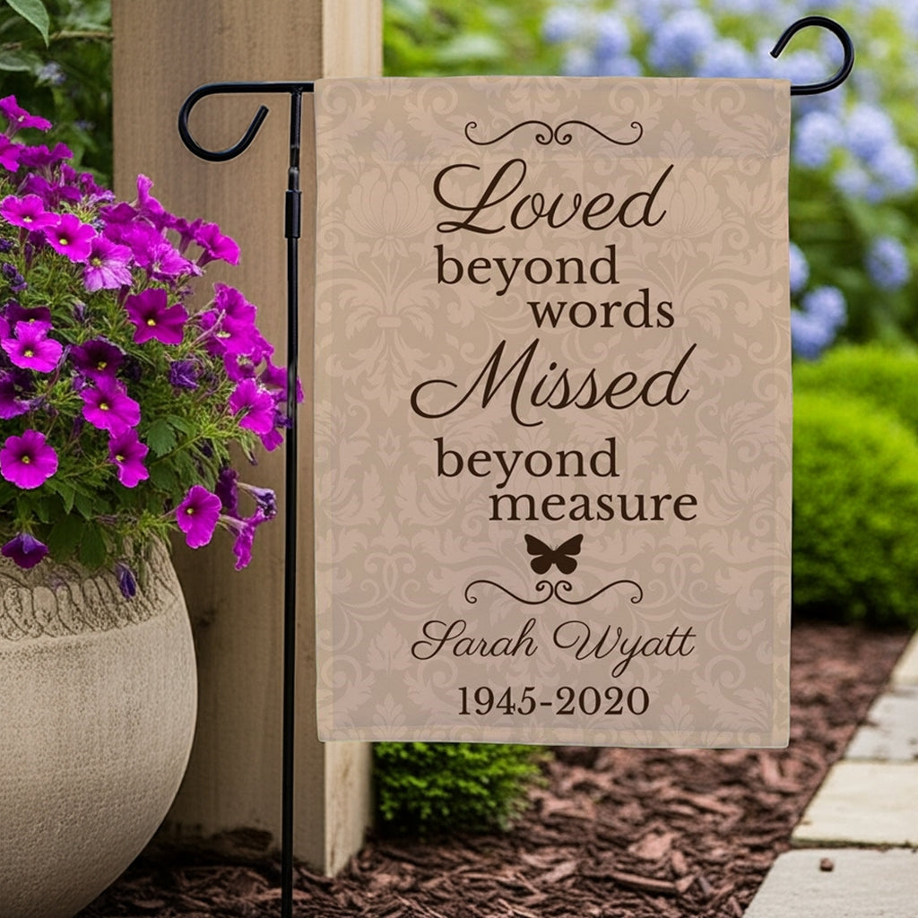 Loved beyond words personalized memorial garden flag displayed in garden with purple flowers