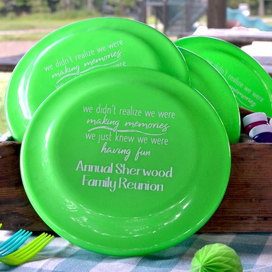 Bright green plastic flying discs personalized for family reunion favors on a picnic table at an outdoor park