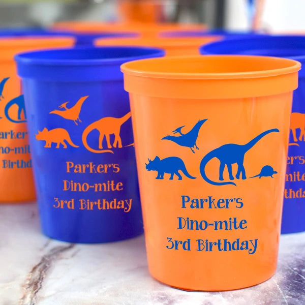 Orange & blue color plastic birthday party cups personalized with dinosaurs design and 3 lines of custom text in contrasting blue and orange print