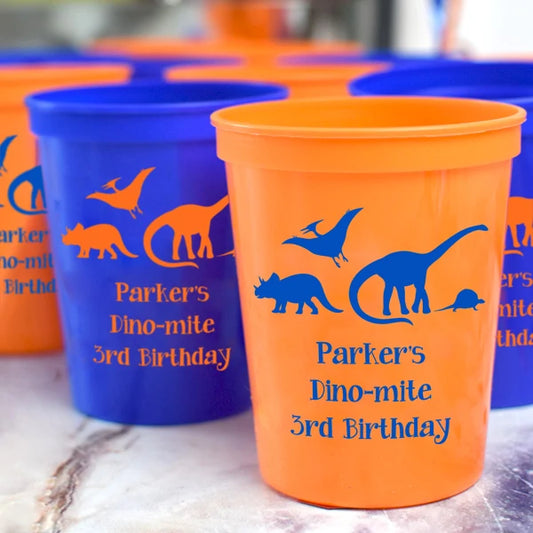 Orange & blue color plastic birthday party cups personalized with dinosaurs design and 3 lines of custom text in contrasting blue and orange print