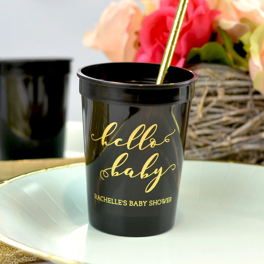 Black 12 ounce size baby shower stadium cups personalized with hello baby design and two line of custom text in gold print on paper plate