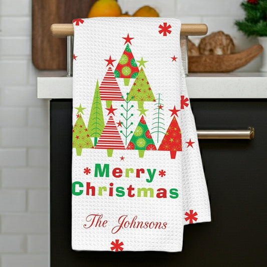 Personalized Christmas kitchen towel featuring festive trees and 'Merry Christmas' with custom printed family name
