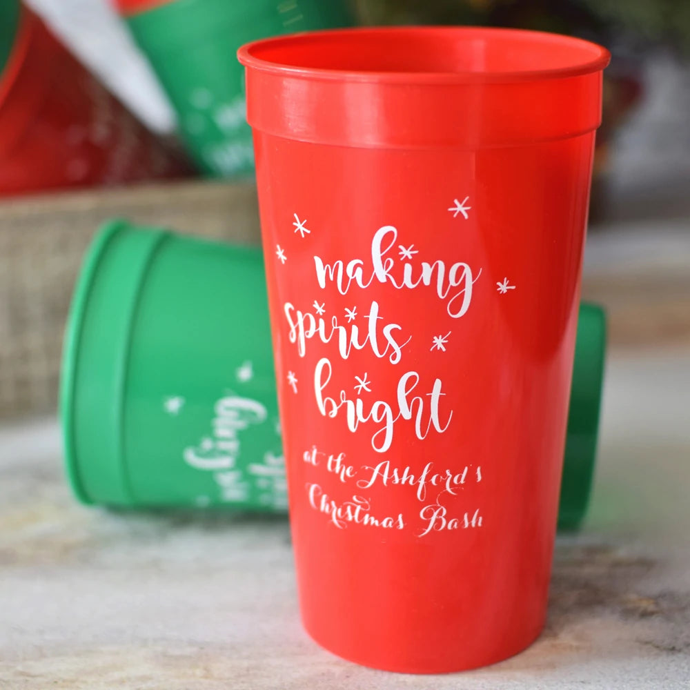 Red personalized Christmas party stadium cups with festive white lettering from Tippytoad