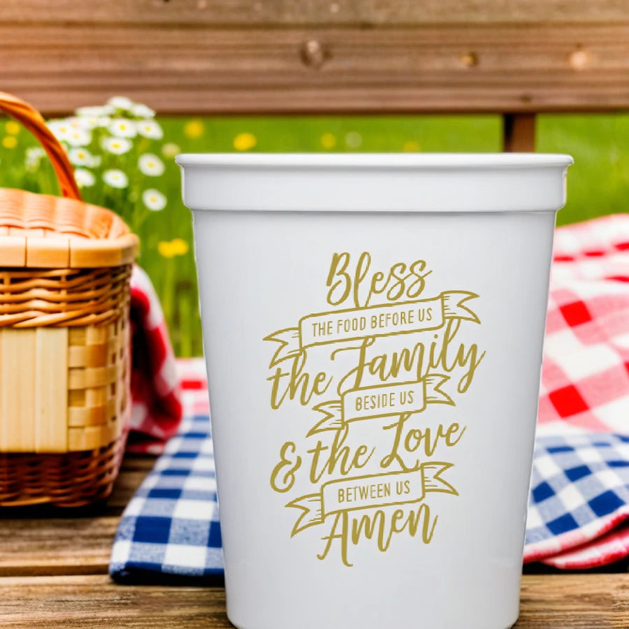 White personalized family reunion cups with gold blessing text on wooden table with picnic basket