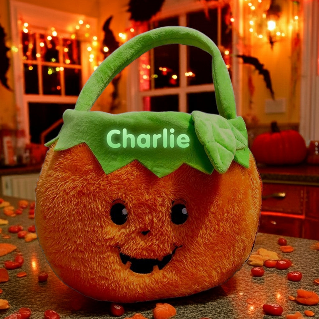 Personalized glow in the dark trick or treat basket shaped like a plush pumpkin with green handle and custom name Charlie