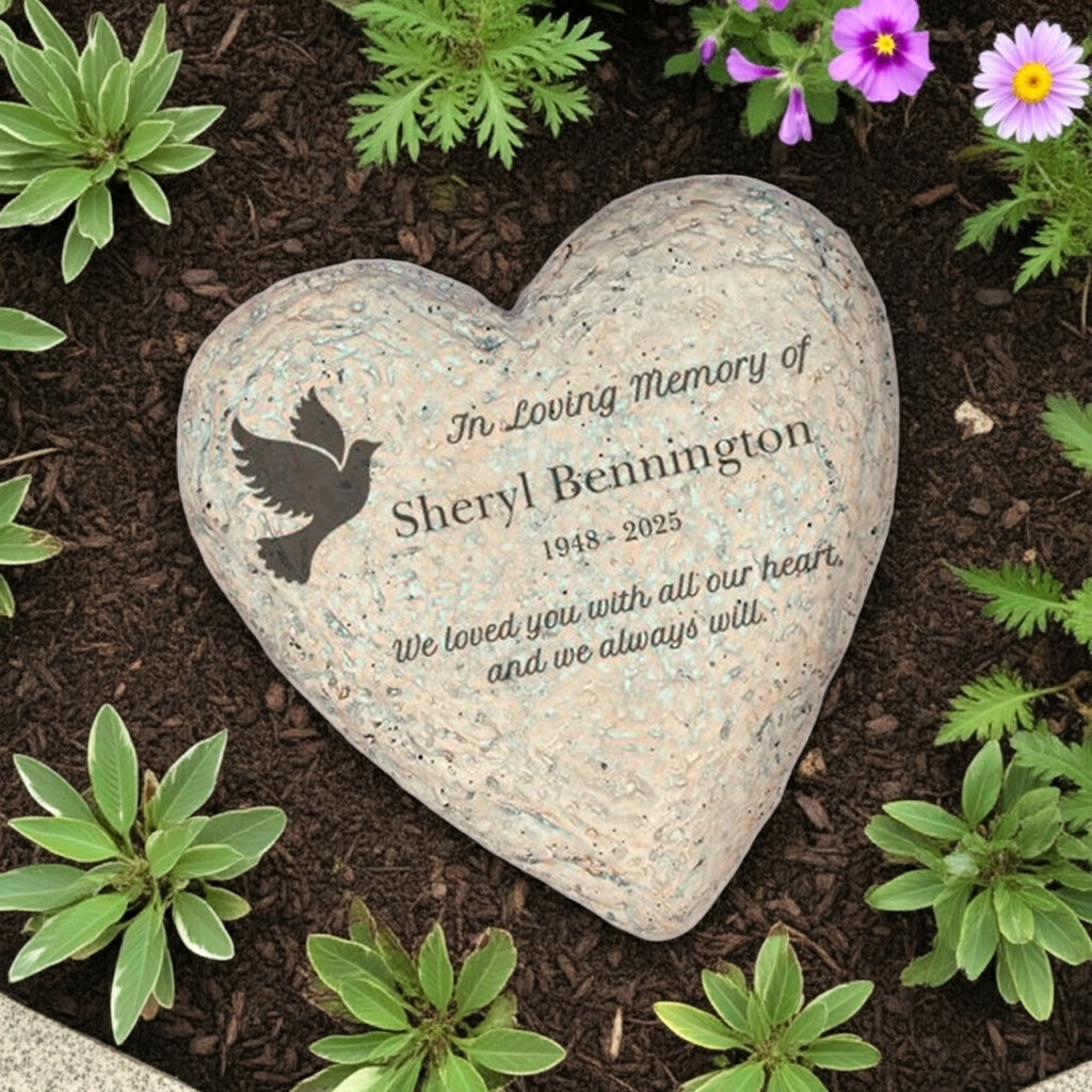 Heart-shaped personalized memorial garden stone engraved with a dove and loving tribute in a garden setting