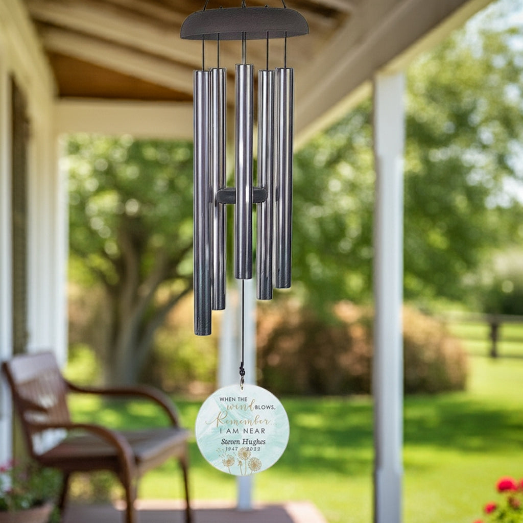 Personalized memorial wind chime hanging on porch with engraved round ornament