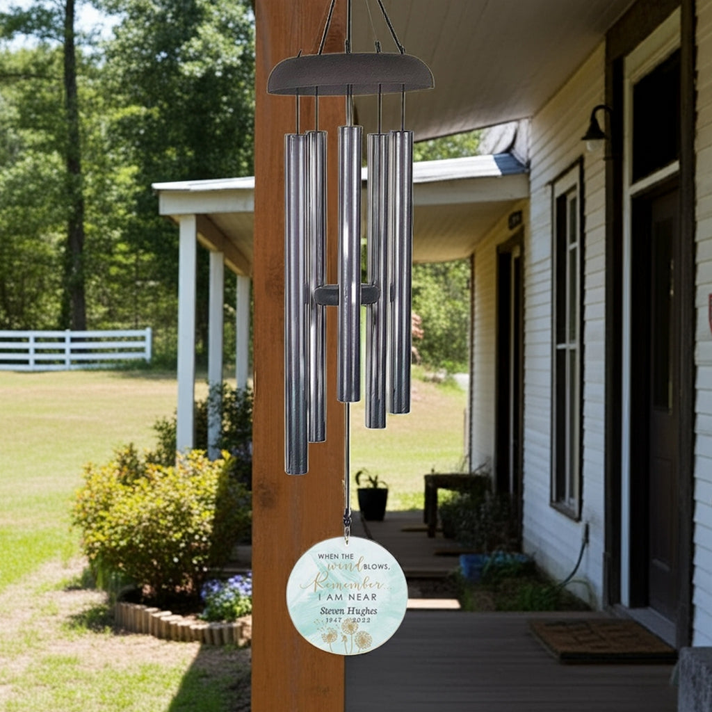 Personalized memorial wind chime hanging on porch post with silver tubes and custom engraved round tag