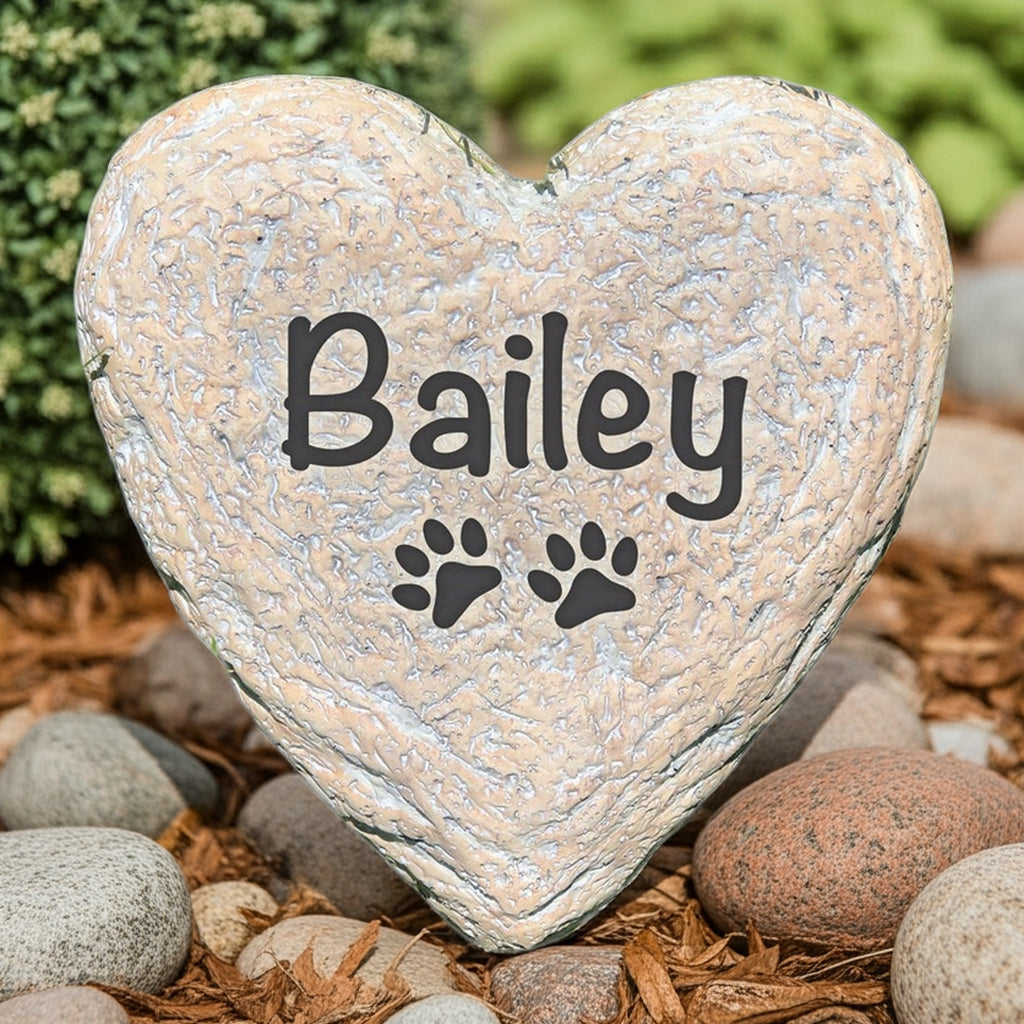 Heart-shaped personalized pet memorial stone with pet name Bailey and paw prints in garden setting