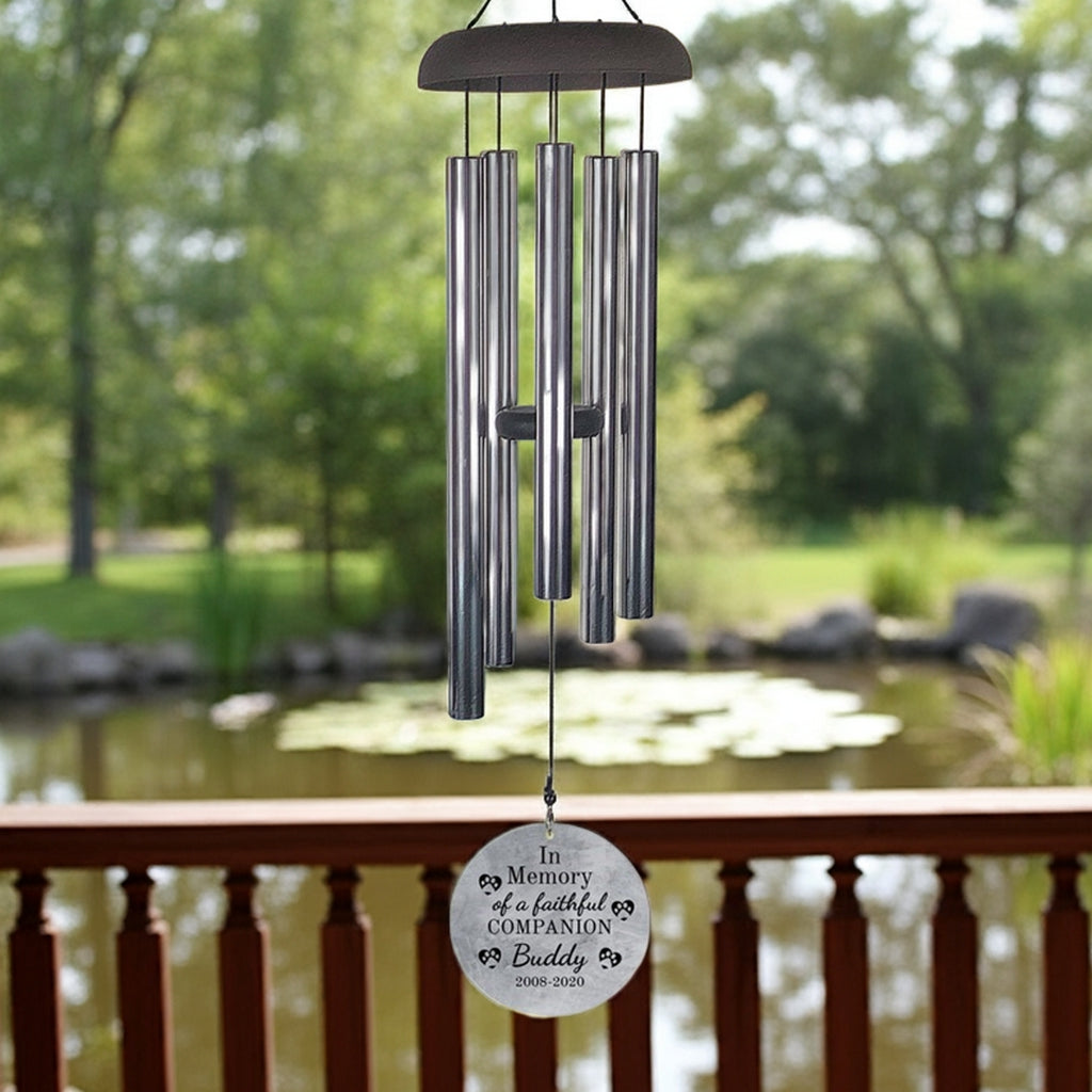Personalized pet memorial wind chime with engraved companion tribute hanging by a pond