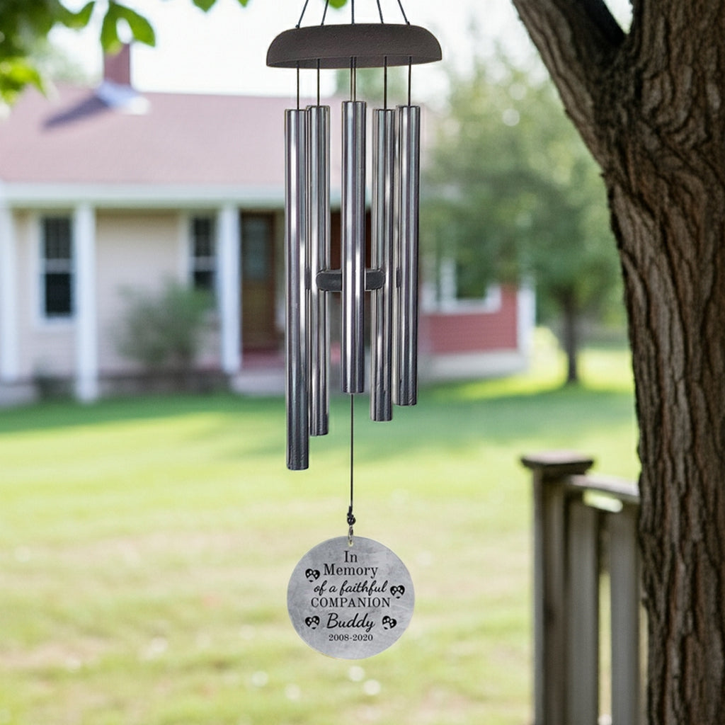 Personalized pet memorial wind chime hanging from tree with engraved round tag for remembrance