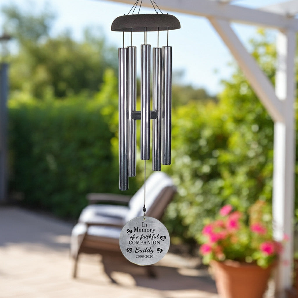 Personalized pet memorial wind chime with metal tubes and custom engraved round pendant hanging outdoors