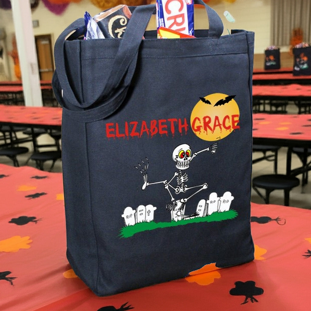 Navy Halloween tote with skeleton graveyard design and Elizabeth Grace name filled with candy personalized trick or treat bag