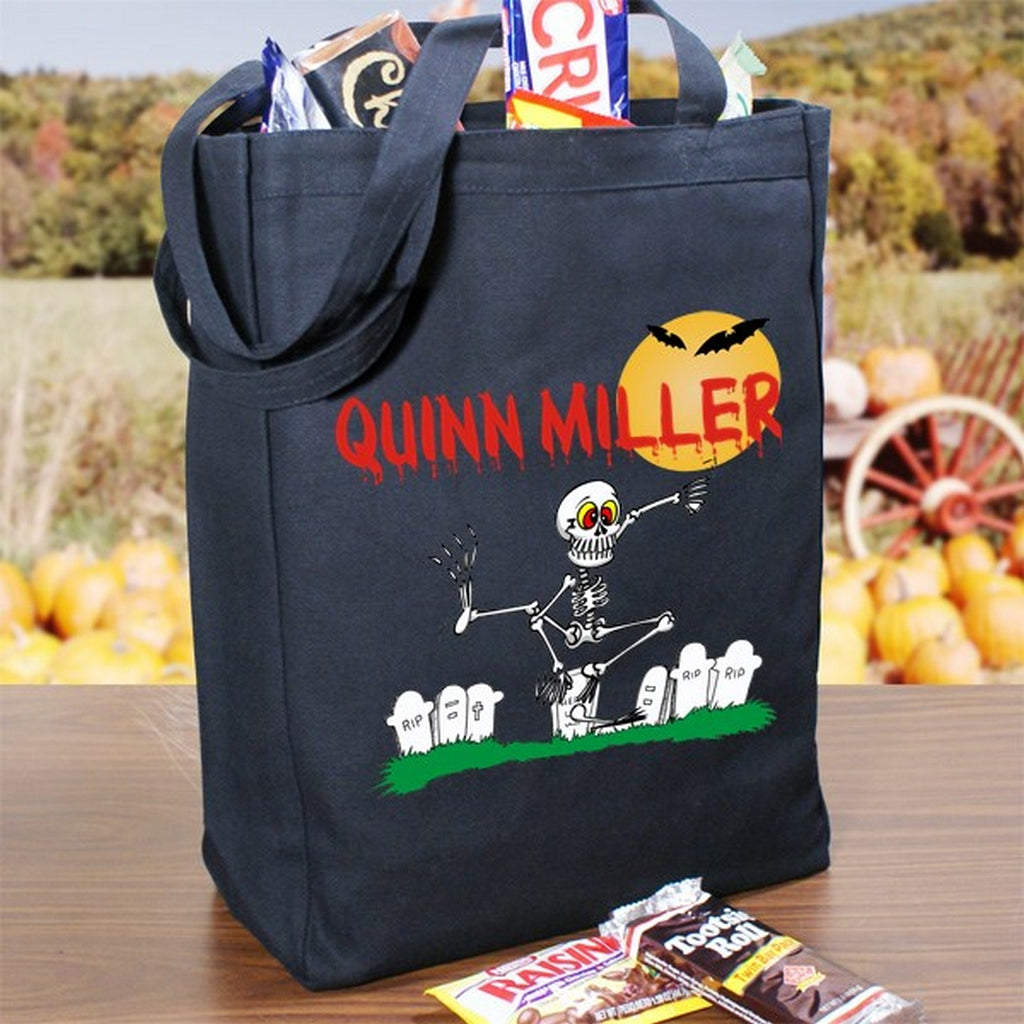 Black personalized trick or treat bag with skeleton graveyard design and red name Quinn Miller filled with candy