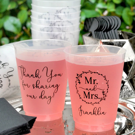 Clear frosted 16 ounce plastic cups personalized with 'Mr. and Mrs. Wreath' wedding design and 1 line of text on the front and 3 lines of custom text on the back in black imprint color