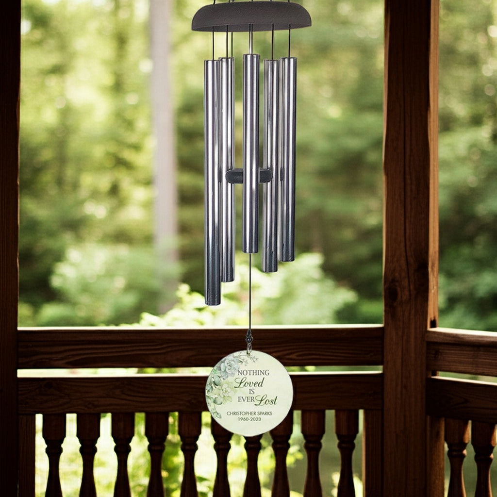 Personalized wind chime memorial with engraved round pendant hanging in a wooden porch setting