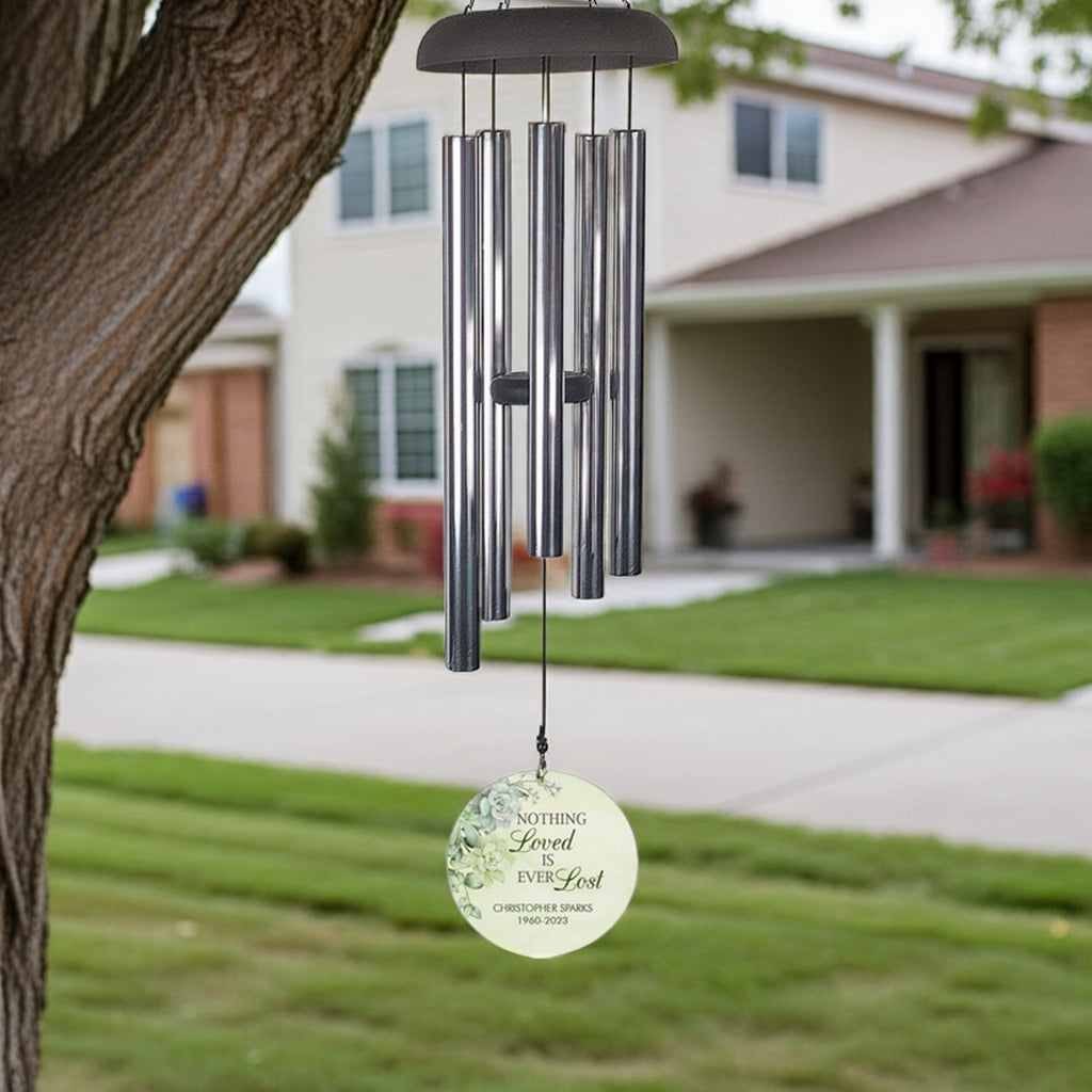 Personalized wind chime memorial hanging from tree with engraved round metal wind sail