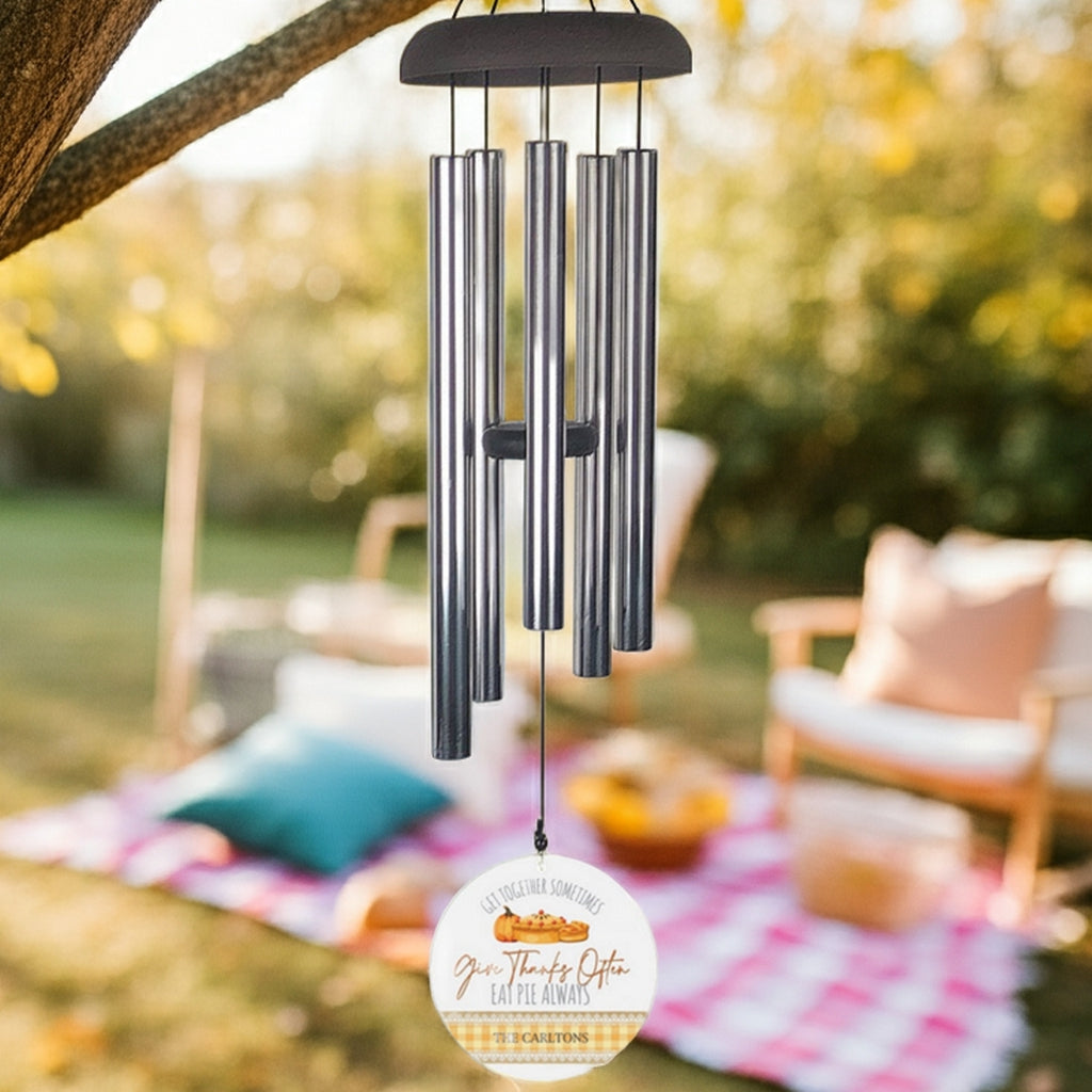 Personalized wind chime with metal tubes hanging outdoors over picnic blanket