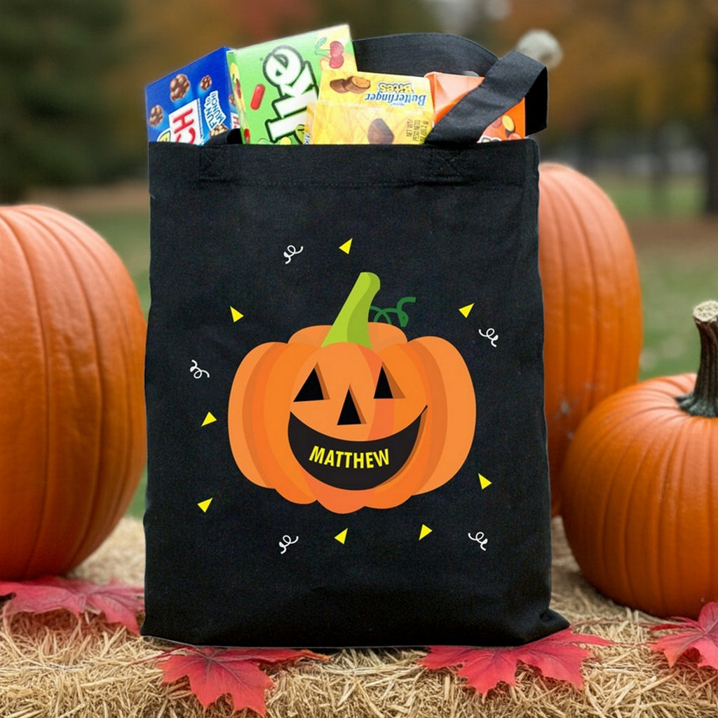 Black tote bag with smiling jack o lantern labeled Matthew filled with candy pumpkin personalized trick or treat bag