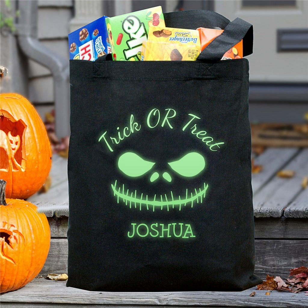 Black tote with glowing green monster face and Joshua filled with candy glow in the dark monster personalized trick or treat bag