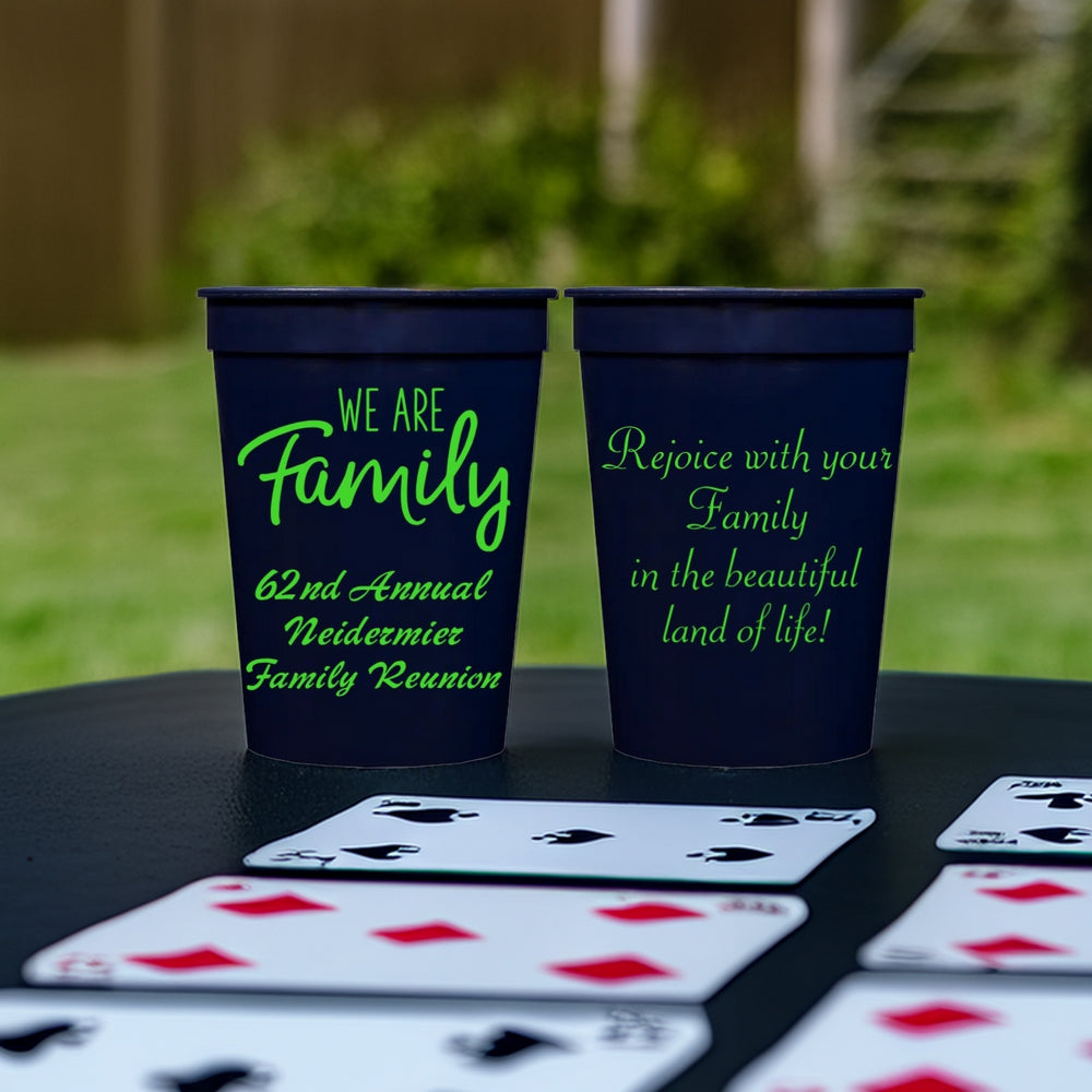 Two navy cups personalized for family reunion favors with "We Are Family" graphic, and custom text on the front and back side in neon green print