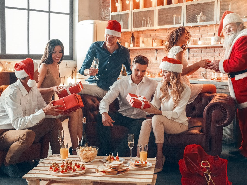 Family members exchanging gifts around a table with appetizers at Christmas party