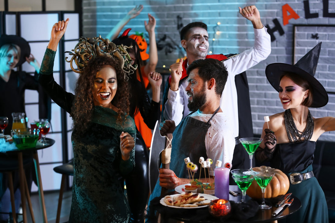 Group of friends celebrating with costumes during halloween party planning event with food and drinks
