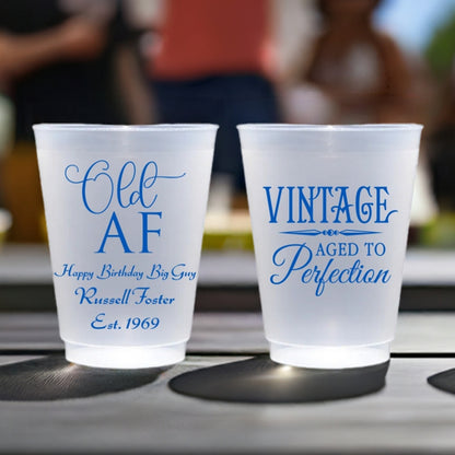 Frosted plastic milestone birthday cups personalized with 'Old AF' design and custom text on front side and 'Vintage Aged To Perfection' design on back side in light blue print. Adult birthday party cups