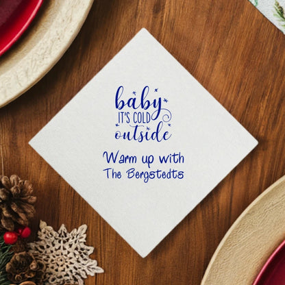 White linen feel luxury Christmas cocktail napkin personalized with Baby It's Cold Outside design and custom text in royal blue print