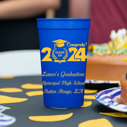 Large blue graduation stadium cups personalized with class of 2024 bold cap design and custom text in yellow print for graduation party favor