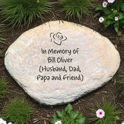 Custom engraved memorial garden stone with In Memory of inscription surrounded by greenery and flowers