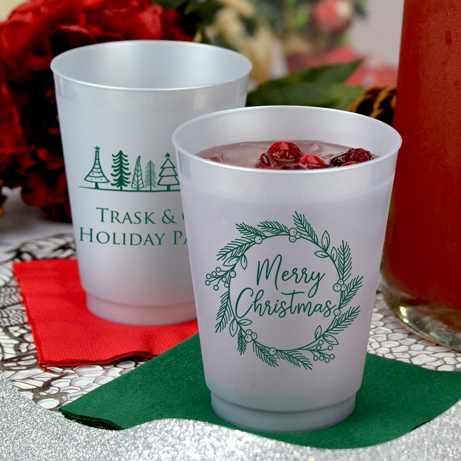 Silver frosted 16 oz. cups personalized with 'Merry Christmas Wreath' design on the front and 'Holiday Trees' design on the back in forest green imprint color